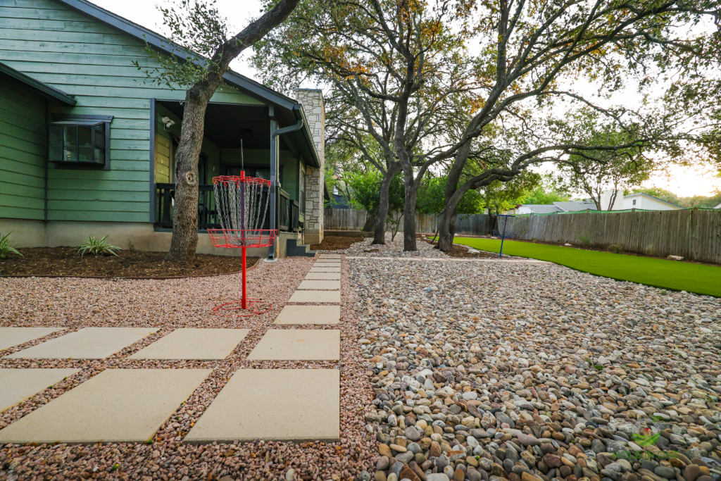 Low-maintenance gravel backyard with stepping pads and a disc golf target