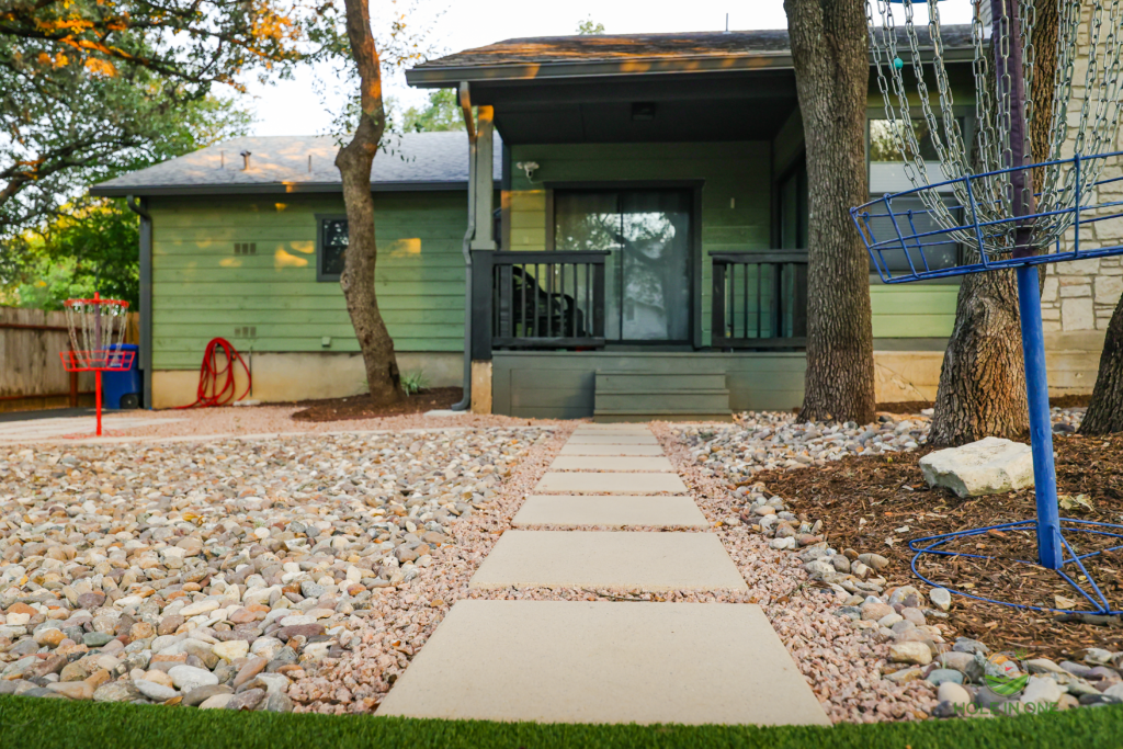 Concrete stepping pad walkway through gravel to the back porch of a green home
