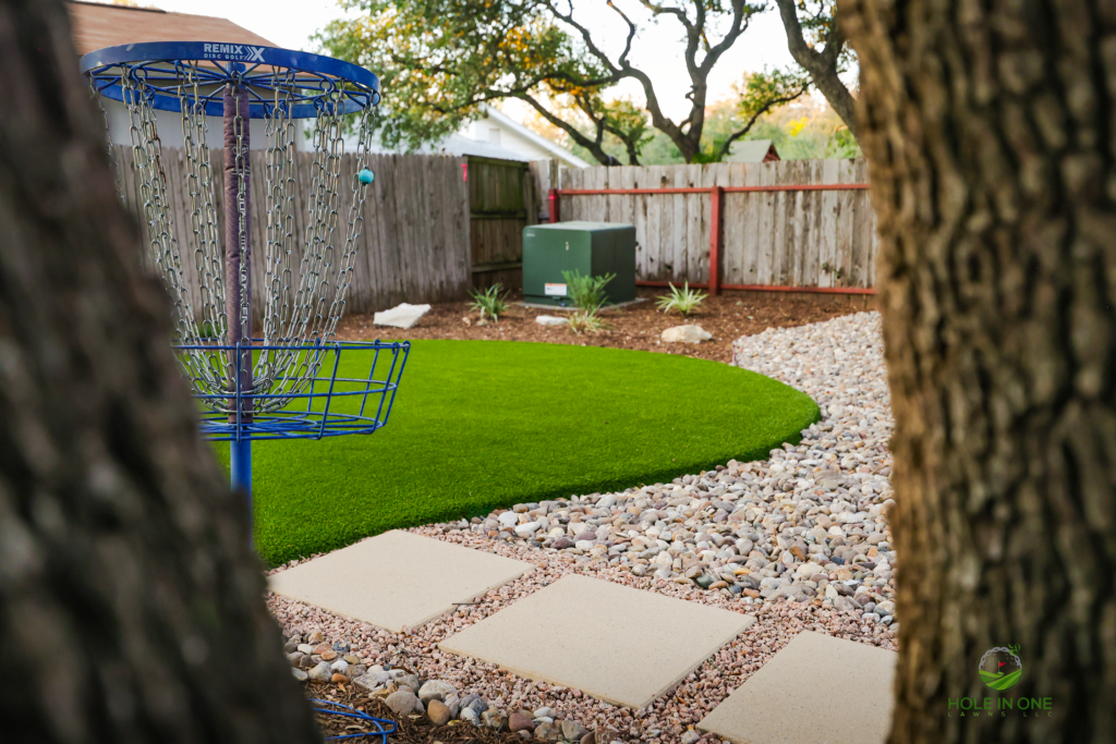 Stepping-pad path between artificial turf and gravel with a disc golf basket