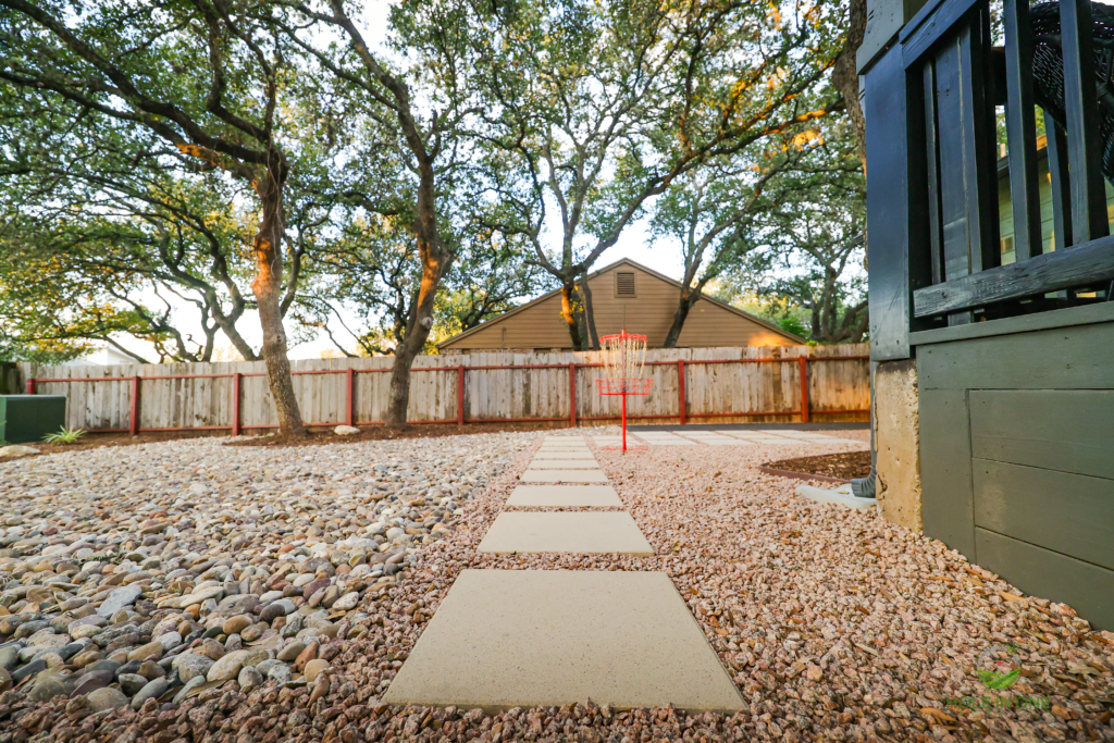 Straight stepping-pad walkway through gravel leading to a backyard fence