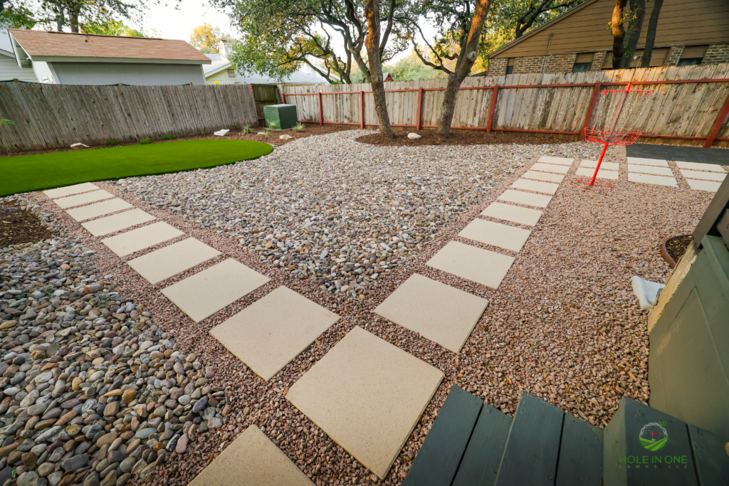 Square concrete stepping pads in pea gravel along a red cedar fence