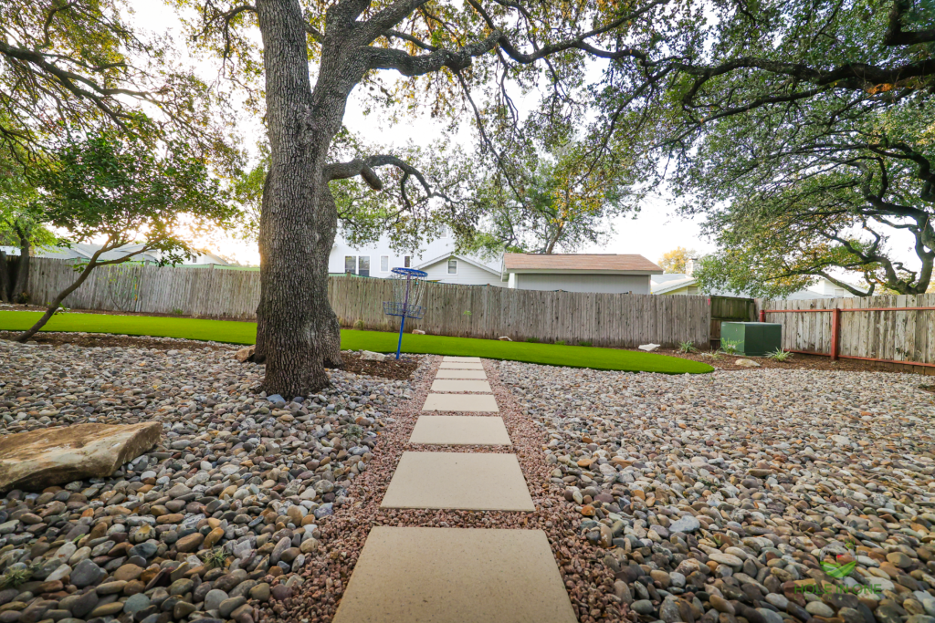 Concrete stepping pad path through pea gravel beside a large live oak