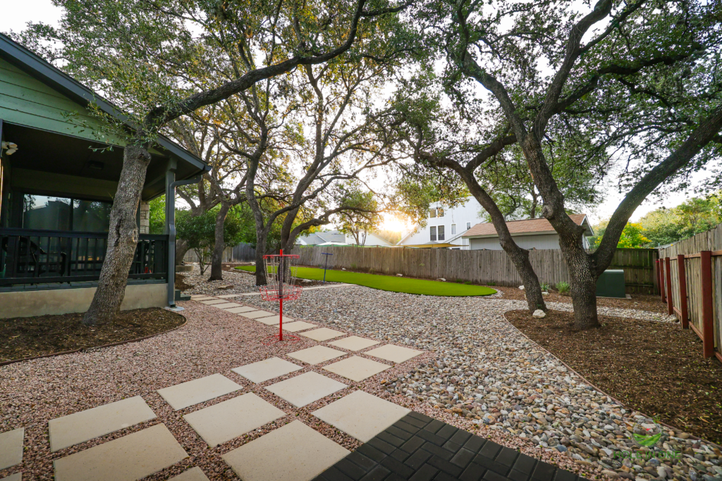 Gravel and stepping-pad backyard path with brick paver edging under mature live oaks