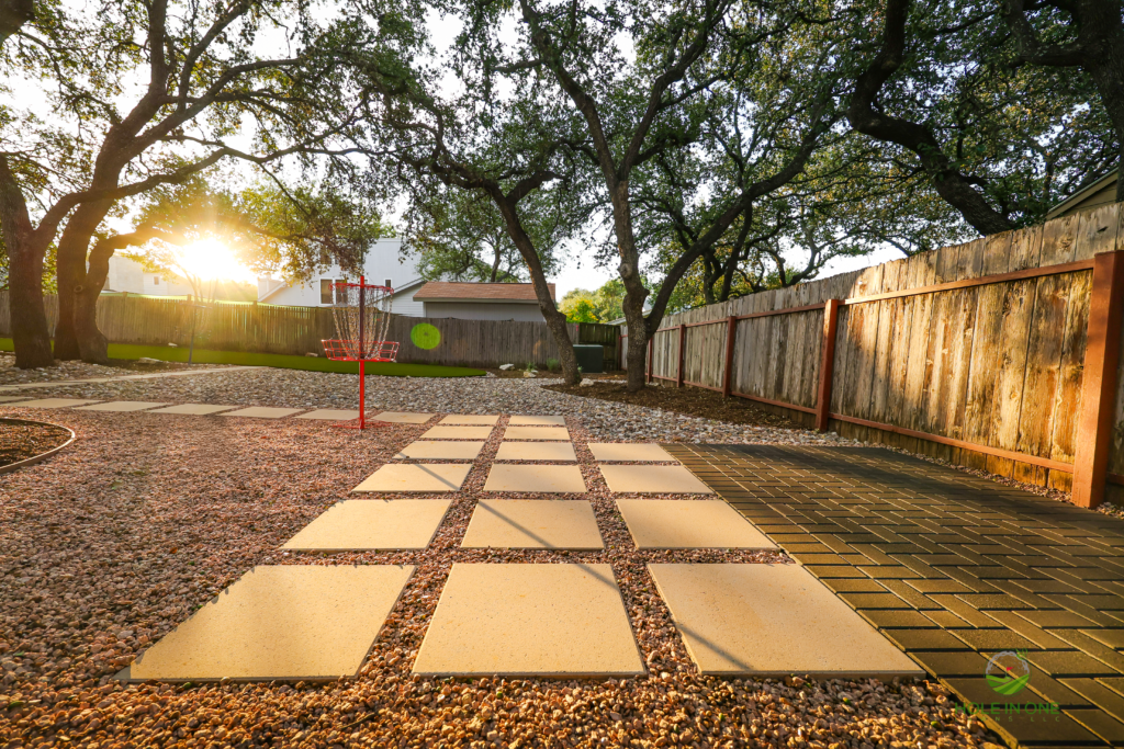 Large concrete stepping pads in gravel forming a backyard path to a disc golf target