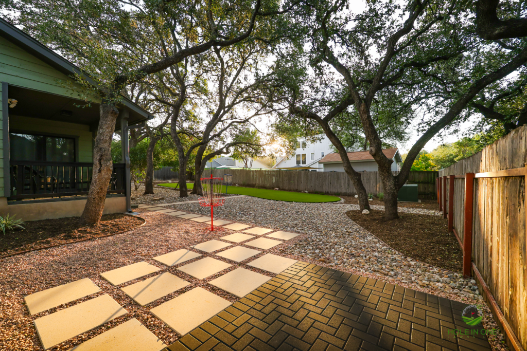 Square concrete stepping pads set in gravel leading from a brick paver patio under oaks