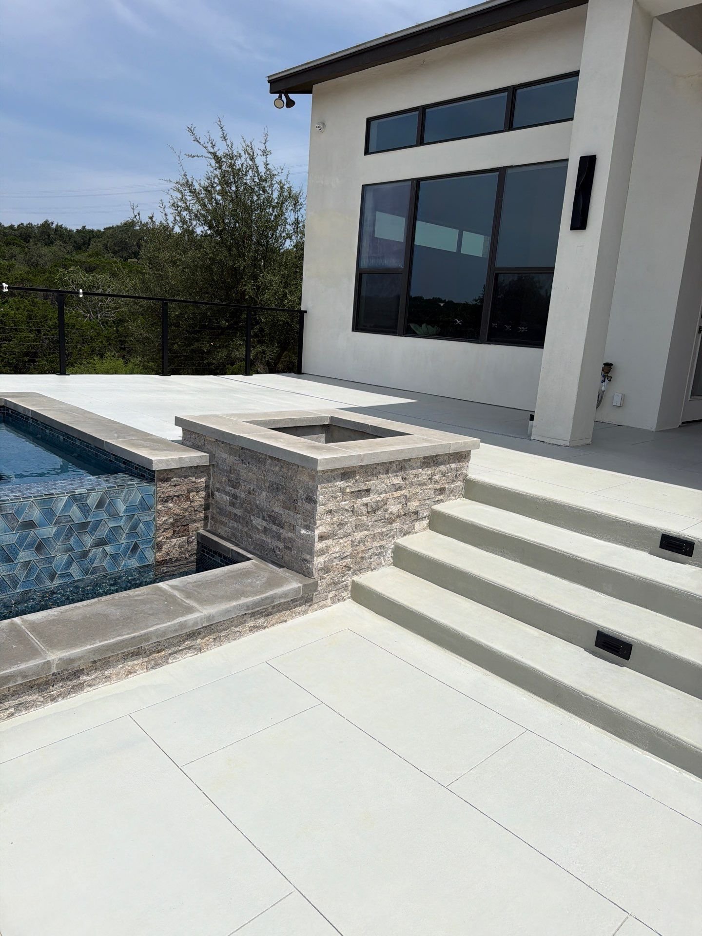 Wide porcelain paver steps and a stacked-stone planter beside a pool deck in Bulverde, TX