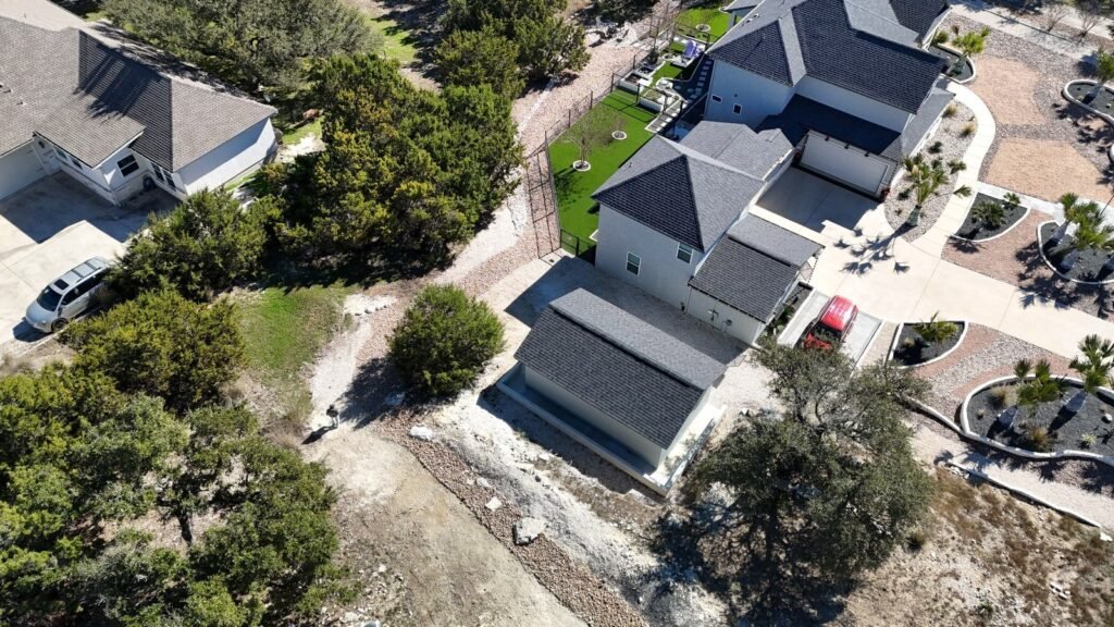 Aerial of curved palm beds and granite front landscape at a Canyon Lake, TX home