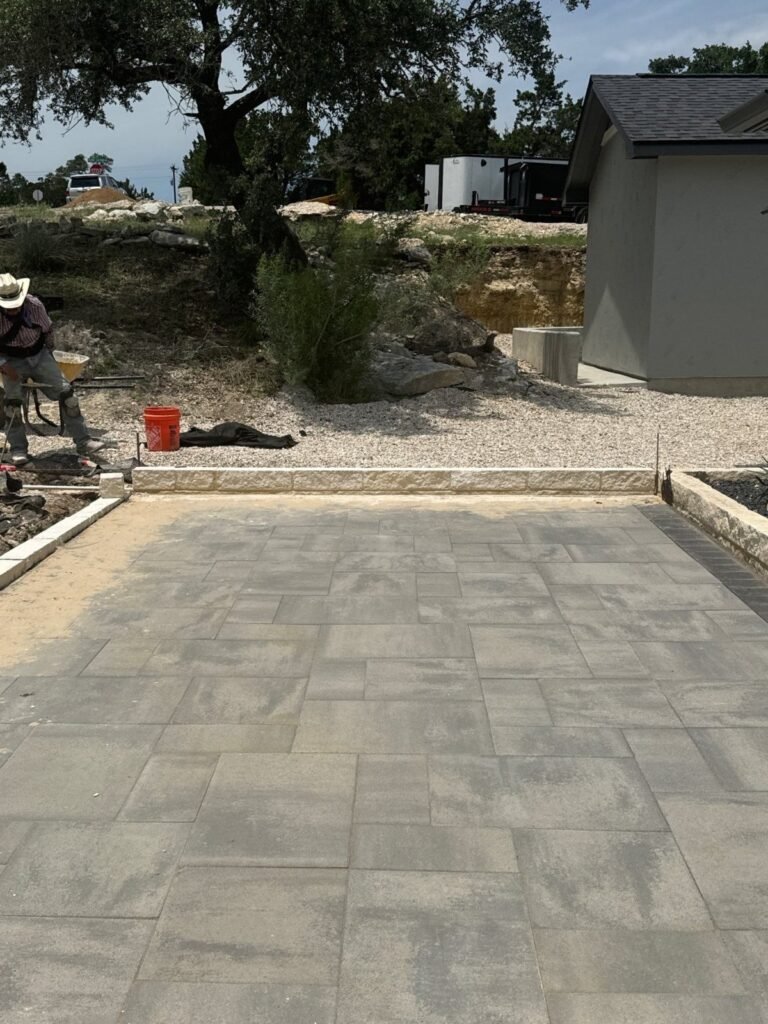Gray Belgard paver patio with limestone edging under Hill Country oaks in Canyon Lake, TX