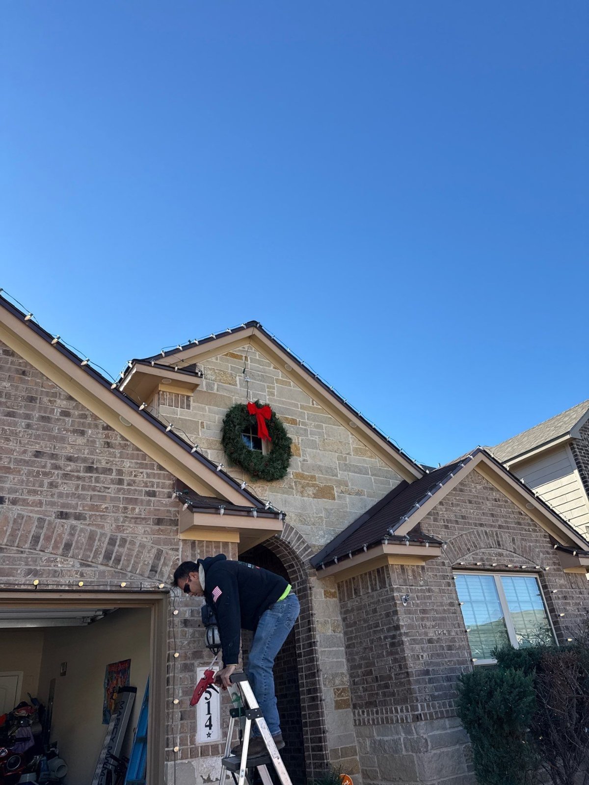 Hole In One Lawns crew hanging Christmas lights along the roofline of a San Antonio home