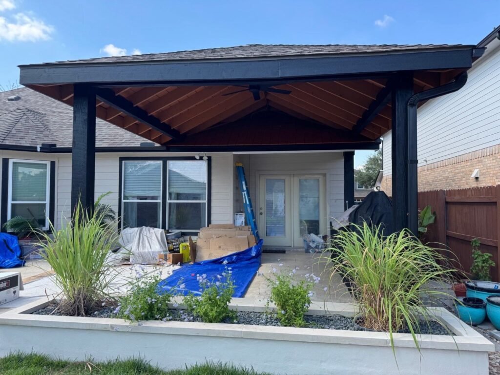 New covered patio pavilion behind a raised planter with ornamental grasses in Cibolo, TX