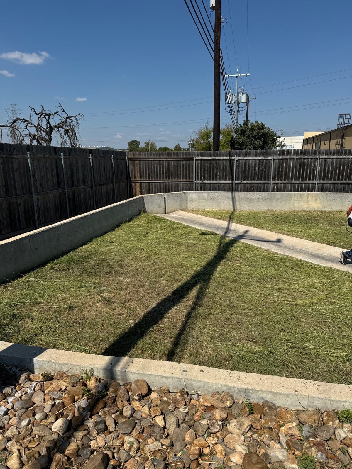Fresh sod between retaining walls and a concrete walkway at a commercial property in Schertz, TX