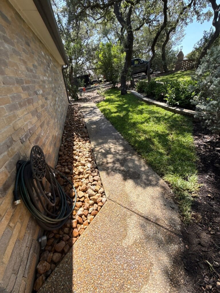 New perennial planting bed with accent boulders and mulch beneath a live oak in Fair Oaks Ranch, TX
