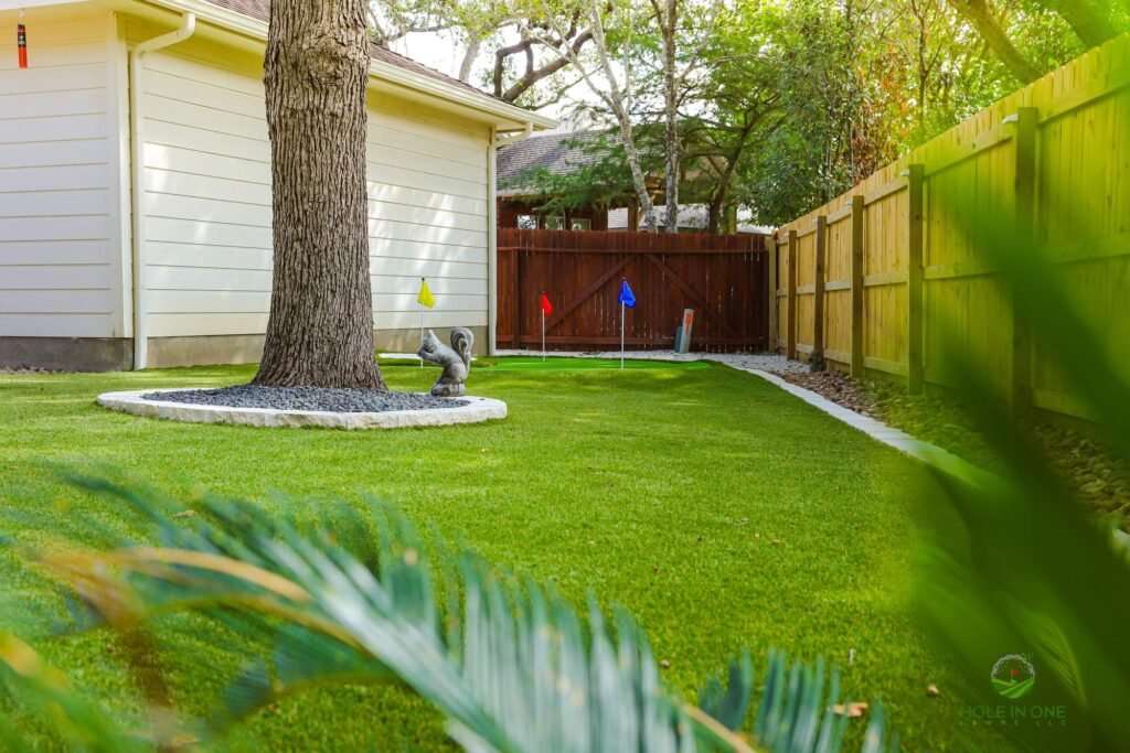 Full synthetic turf backyard with tree ring and concrete curb edging along a cedar fence in Helotes, TX