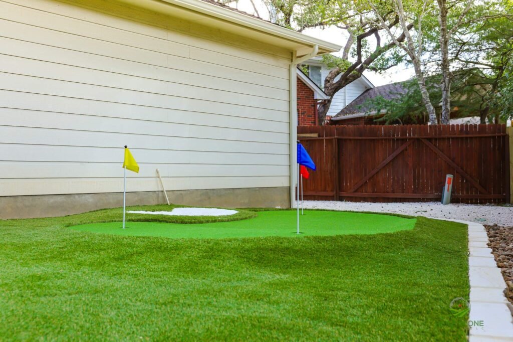Two-cup artificial putting green set in synthetic turf lawn beside a home in Helotes, TX