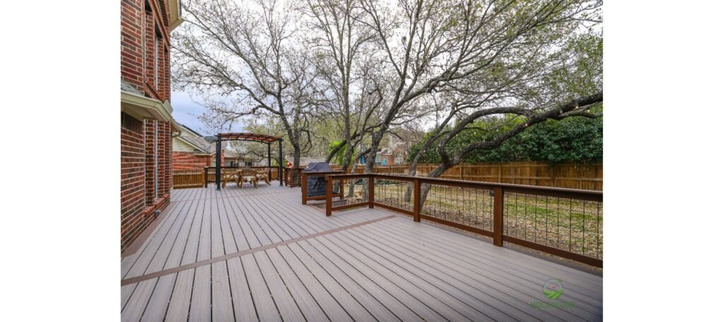 Large Trex deck under mature oaks with wood-and-wire railing and a pergola