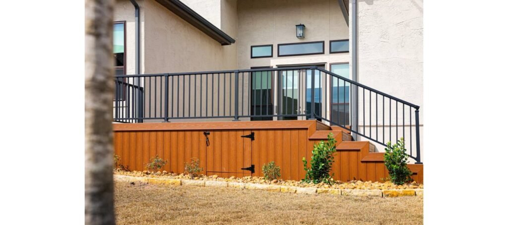 Raised Trex deck with black metal railing and Trex skirting with a storage access door