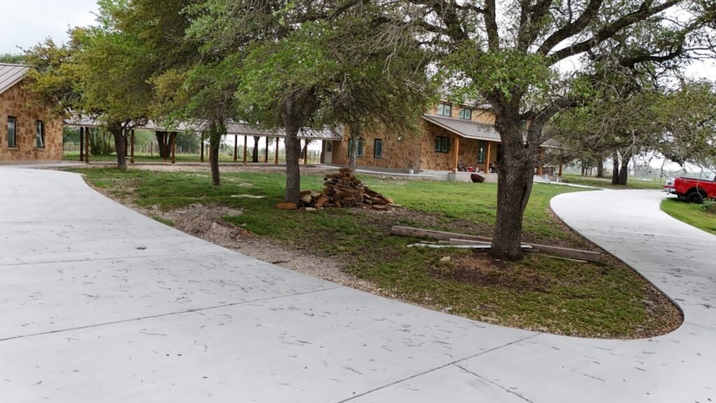 Mature oaks and lawn beside a sweeping concrete drive at a ranch home near Seguin, TX