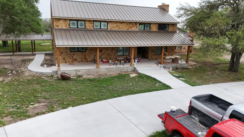Aerial of a stone ranch home with a curved concrete walk and lawn near Seguin, TX