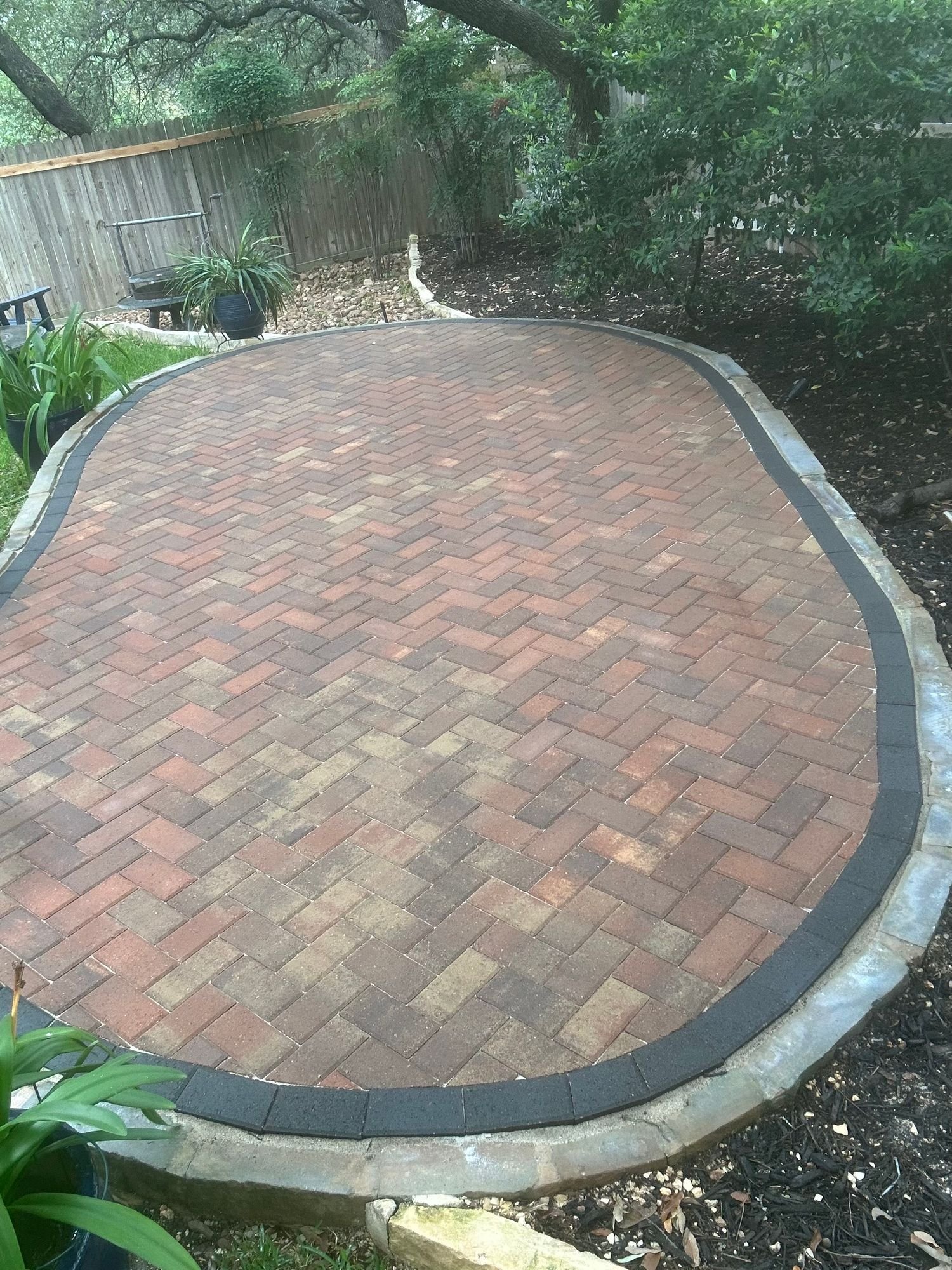 Oval herringbone clay-brick paver patio with a charcoal border in Stone Oak, San Antonio