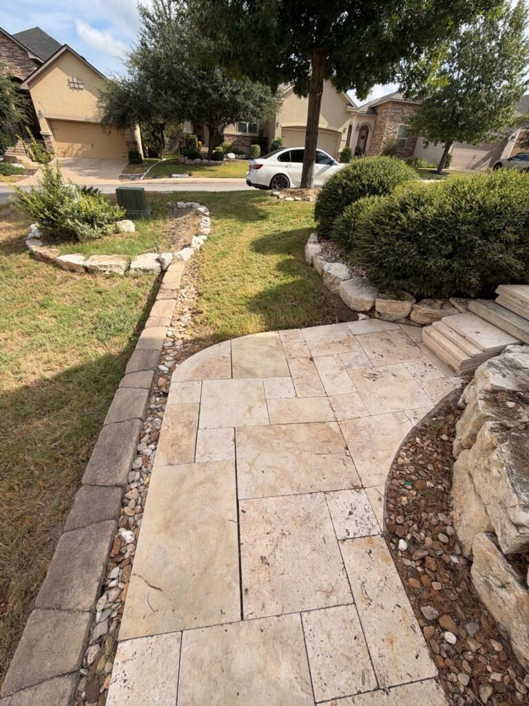 Travertine paver front walkway with limestone boulder bed and river rock edging at a Stone Oak, San Antonio home