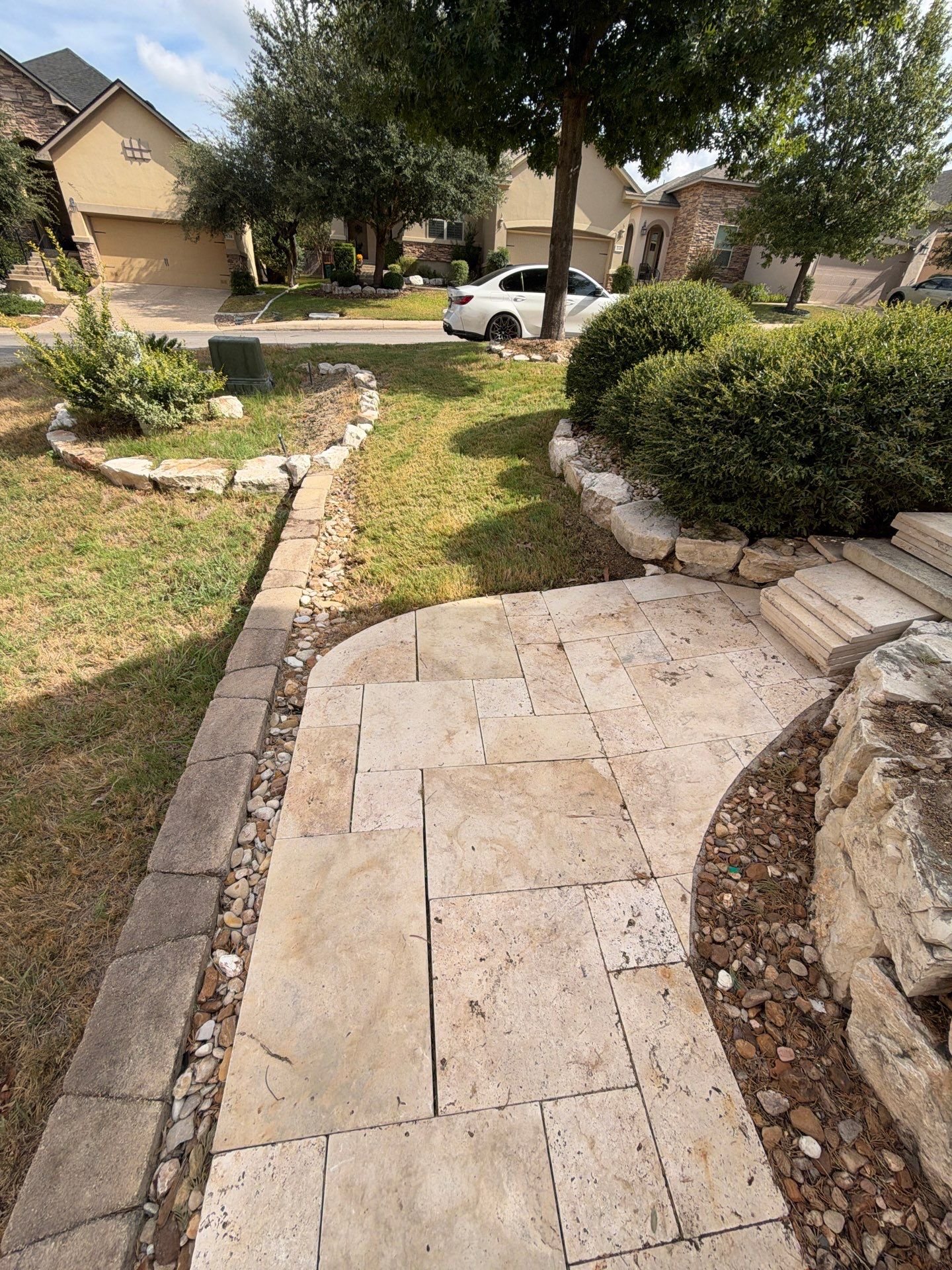 Travertine paver front walkway with a limestone boulder bed in Stone Oak, San Antonio